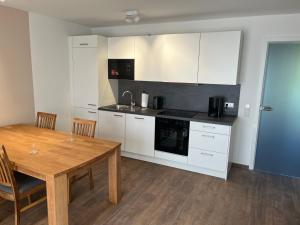 a kitchen with white cabinets and a wooden table at Apartments Blütenweg in Leichlingen