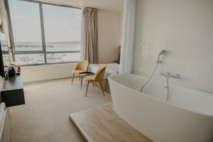 a bathroom with a bath tub and a bedroom at Le Nautica Hôtel in Perros-Guirec +55 photos