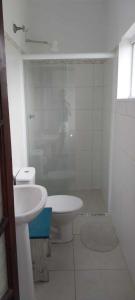 a white bathroom with a toilet and a sink at Apartamento de frente ao mar - Centro in Peruíbe +12 photos