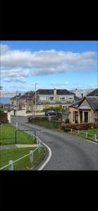 an empty road in a residential neighborhood with houses at Dove Cottage in Greenock