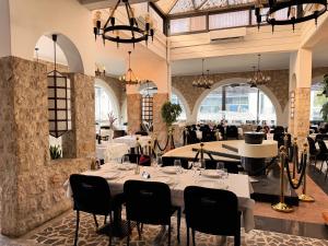 a dining room with white tables and chairs and chandeliers at Tamaris Rooms in Zadar