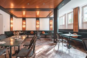 a dining room with tables and chairs and windows at Villa Dora Petit Hôtel in Bad Reichenhall
