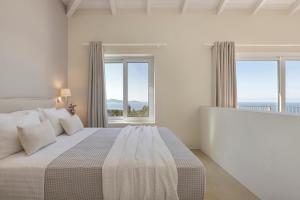 a white bedroom with a large bed with windows at Magganos Sunset Villas in Fiskardo +33 photos
