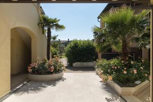 a courtyard with flowers and palm trees and a building at Charme Relax e Terrazza a Vista in Sirmione