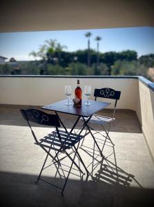a table with two chairs and a bottle and two glasses at B&B Helios in Nardò