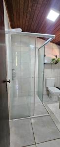 a glass shower in a bathroom with a toilet at Quarto Familiar Centro in Pomerode +6 photos