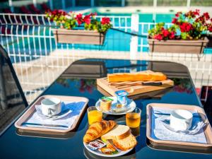a table with two trays of food and coffee and bread at Ibis Budget Hyères in Hyères