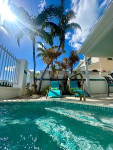a swimming pool with blue chairs and palm trees at Seas the Keys Getaway in Duck Key