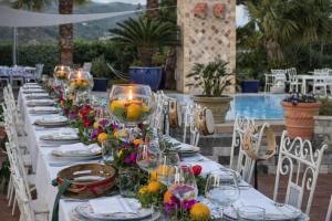 a long table with plates and wine glasses and flowers at Hotiday Villa Neptunus in Forio d'Ischia