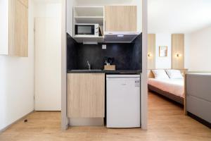 a kitchen with a refrigerator and a bed in a room at Sweetly Bordeaux Mérignac Aeroparc in Mérignac