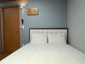 a bedroom with a large white bed with a blue wall at Gyeongju Bee House in Gyeongju
