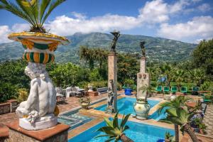 a pool with a statue next to a resort at Hotiday Villa Neptunus in Forio d'Ischia