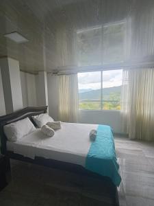 a bed in a bedroom with a large window at Hotel Puerto azul in Chitaraque +12 photos