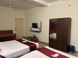 a hotel room with two beds and a tv at Villa The De Grise in Pondicherry +43 photos