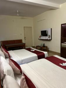 a hotel room with three beds and a television at Villa The De Grise in Pondicherry