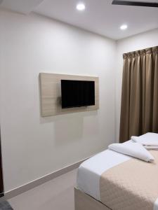 a bedroom with a bed and a tv on the wall at Tresor Hotel in Cochin