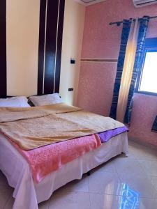 a bedroom with a large bed with a window at Merzouga Roms in Merzouga