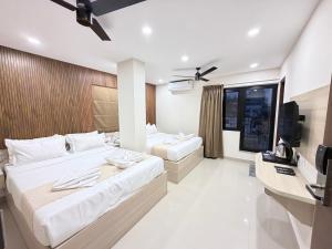 a hotel room with two beds and a television at Tresor Hotel in Cochin