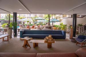 a living room with a blue couch and tables and chairs at Afago Mareiro Hotel in Fortaleza