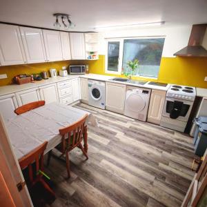 a kitchen with white cabinets and a table and a sink at Treforgan Newydd in Cardigan +20 photos