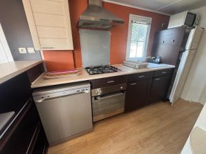 a kitchen with a stove top oven next to a sink at MH Camping la plage - MarieVa in Mimizan-Plage
