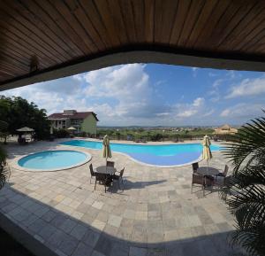 a swimming pool with chairs and umbrellas next to it at Flat Vila Monte Castelo in Gravatá