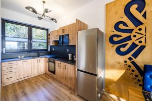 a kitchen with wooden cabinets and a stainless steel refrigerator at Chalety v Pieninách in Červený Kláštor