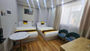 a room with two beds and a table and chairs at Очир зочид буудал in Dalandzadgad