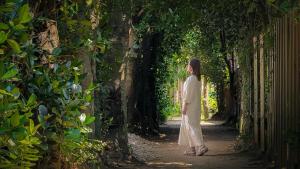 a woman in a white dress walking down a path at 陽月-Hizuki- in Nakijin +59 photos
