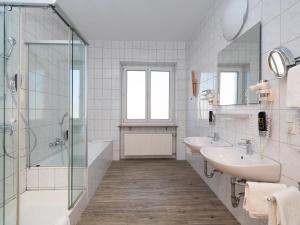 a bathroom with two sinks and a shower at DONAUHOTEL Ingolstadt in Ingolstadt +24 photos