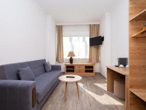 a living room with a blue couch and a table at DONAUHOTEL Ingolstadt in Ingolstadt