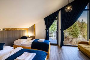a bedroom with two beds and a large window at Chalety v Pieninách in Červený Kláštor