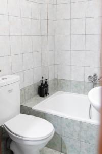 a bathroom with a white toilet and a bath tub at Pineios View New Apartment in Larisa +18 photos