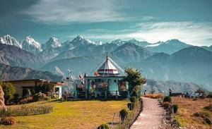 a house on a hill with mountains in the background at Bilju Homestay in Munsyari