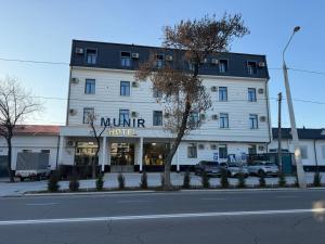 a large white building with a sign for a hotel at Munir Hotel in Chilanzar