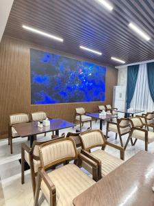 a restaurant with tables and chairs and a large painting at Munir Hotel in Chilanzar