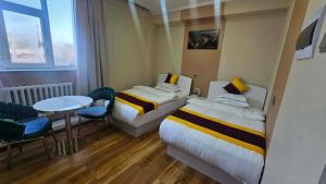 a hotel room with two beds and a table and chairs at Очир зочид буудал in Dalandzadgad +5 photos