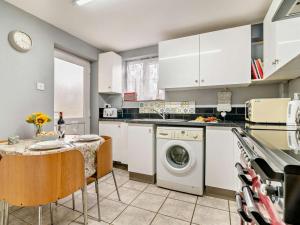 a kitchen with a washing machine and a table with chairs at 1 Bed in Sherborne oc-93804 in Yetminster