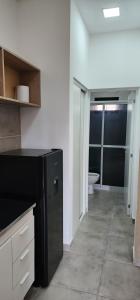 a kitchen with a black refrigerator and a bathroom at Cabaña Loma Linda in Presidencia Roque Sáenz Peña