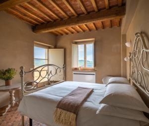 a bedroom with a bed and two windows at Casa in Campagna Casagori in Pienza