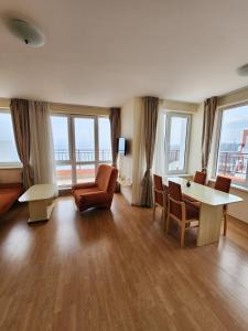 a living room with a table and chairs and windows at Stunning Beach View Apartment in Ravda