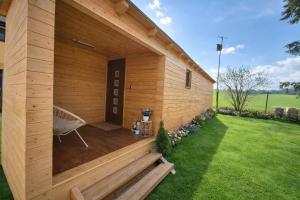 a wooden building with a bench on a lawn at Bee house in Bořanovice