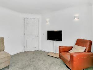 a living room with a leather chair and a flat screen tv at Central Sherborne in Sherborne