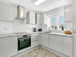a white kitchen with white cabinets and a window at Central Sherborne in Sherborne