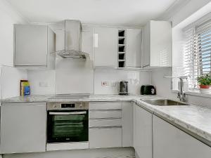 a white kitchen with white cabinets and a sink at Central Sherborne in Sherborne +23 photos
