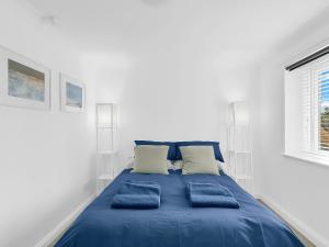 a bed with blue pillows in a white room at Central Sherborne in Sherborne