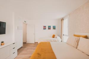 a white bedroom with two beds and a tv at Alojamiento en Santa Eugenia A in Madrid