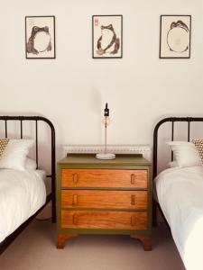 a bedroom with two beds and a wooden dresser between two beds at Seal Cottage in Whitstable