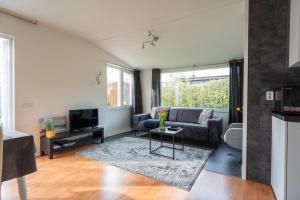 a living room with a couch and a tv at Zonneschijn, bungalow op vakantiepark bij zee in Baarland