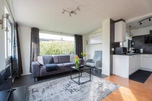 a living room with a couch and a table at Zonneschijn, bungalow op vakantiepark bij zee in Baarland